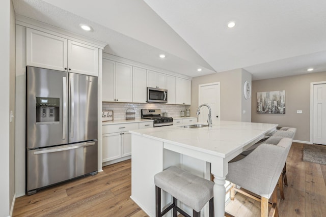 kitchen featuring white cabinets, stainless steel appliances, lofted ceiling, and sink