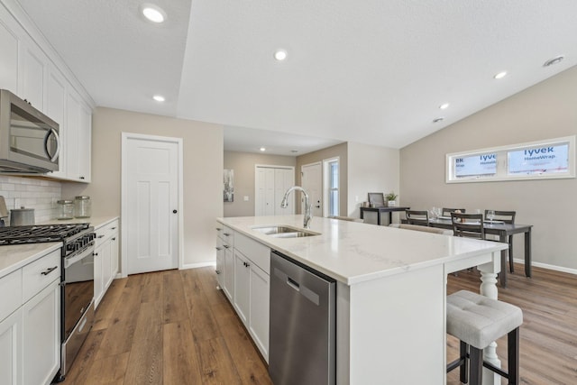 kitchen with sink, white cabinets, stainless steel appliances, and a center island with sink