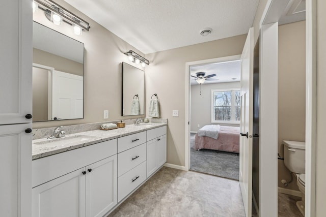 bathroom with ceiling fan, vanity, a textured ceiling, and toilet