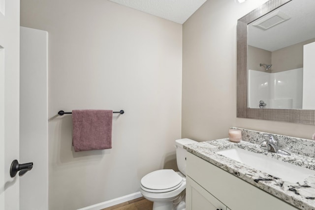 bathroom featuring a shower, a textured ceiling, vanity, and toilet