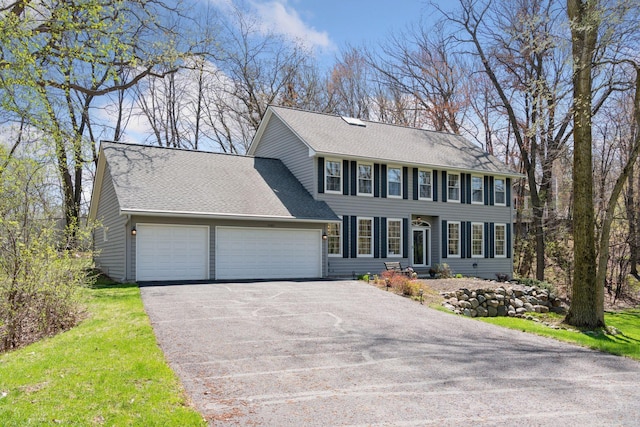colonial house with a garage, roof with shingles, and aphalt driveway