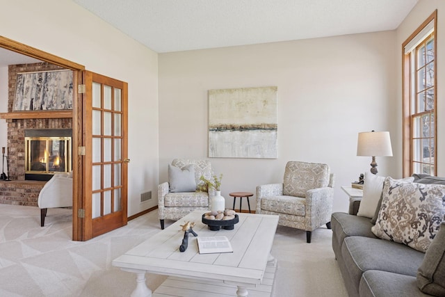 living area with a brick fireplace, light colored carpet, and visible vents
