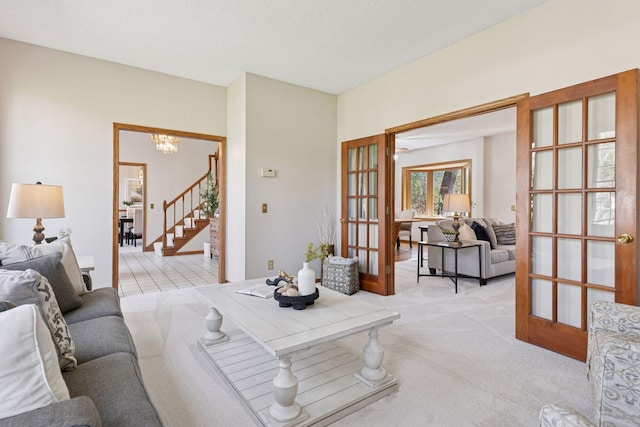 living room with stairs, an inviting chandelier, light carpet, and french doors