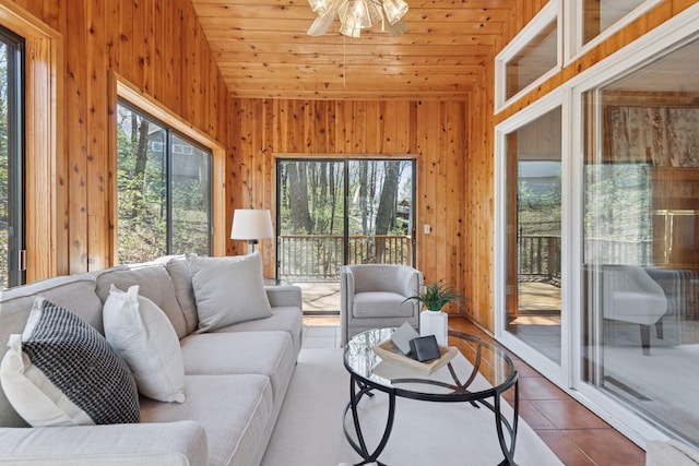 tiled living area with a ceiling fan, wood walls, wooden ceiling, and lofted ceiling