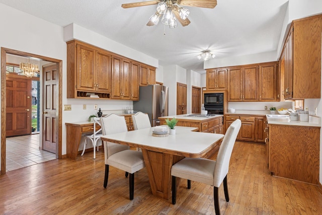 kitchen featuring brown cabinetry, a breakfast bar area, a center island, light countertops, and black appliances