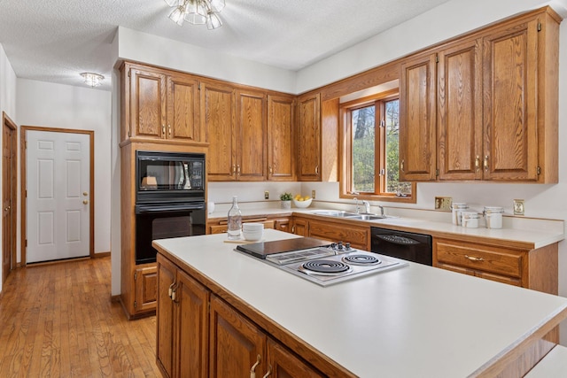 kitchen featuring brown cabinetry, a sink, black appliances, and light countertops