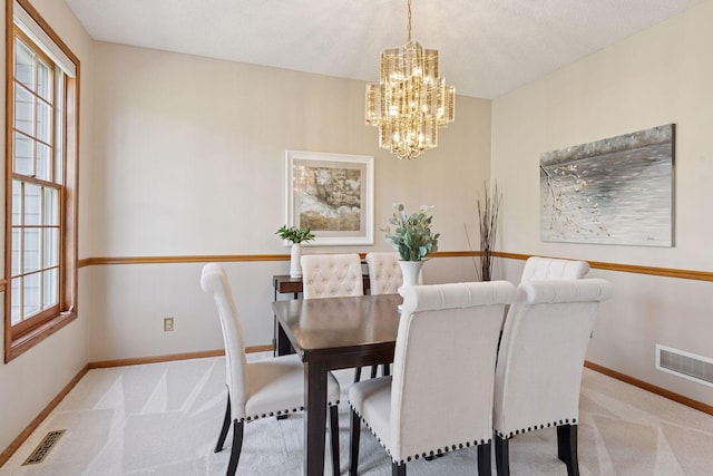 carpeted dining room featuring baseboards, a notable chandelier, and visible vents