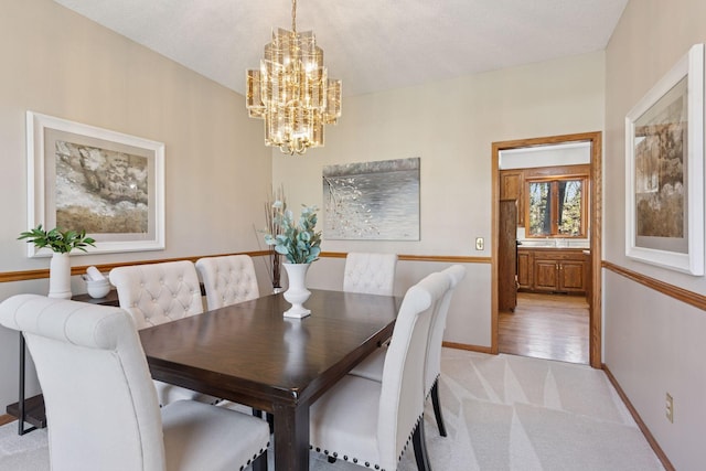 dining area featuring baseboards, light colored carpet, and a chandelier