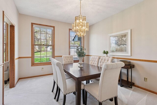 dining room with light colored carpet, baseboards, and a notable chandelier
