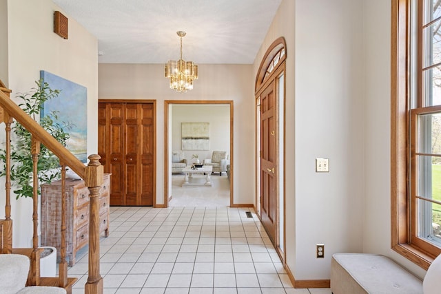 entryway with stairway, light tile patterned floors, baseboards, and a chandelier