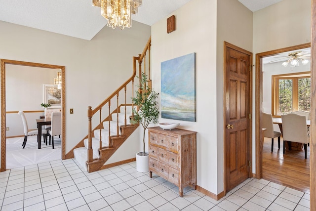 staircase featuring baseboards, tile patterned flooring, and ceiling fan with notable chandelier