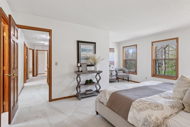 bedroom with a textured ceiling, light carpet, and baseboards