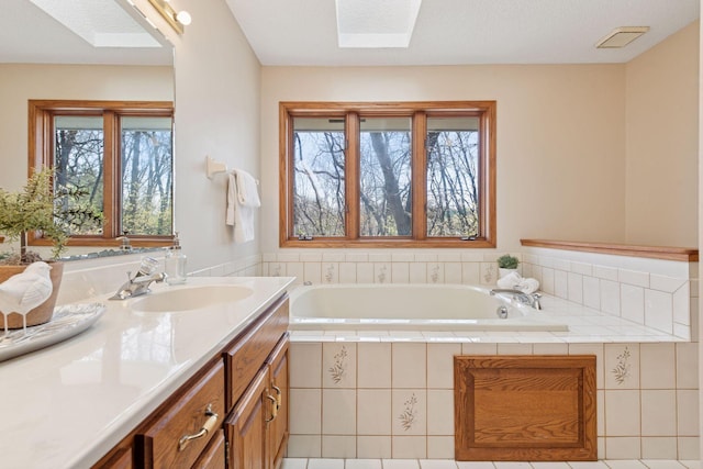 bathroom featuring a skylight, a bath, and vanity