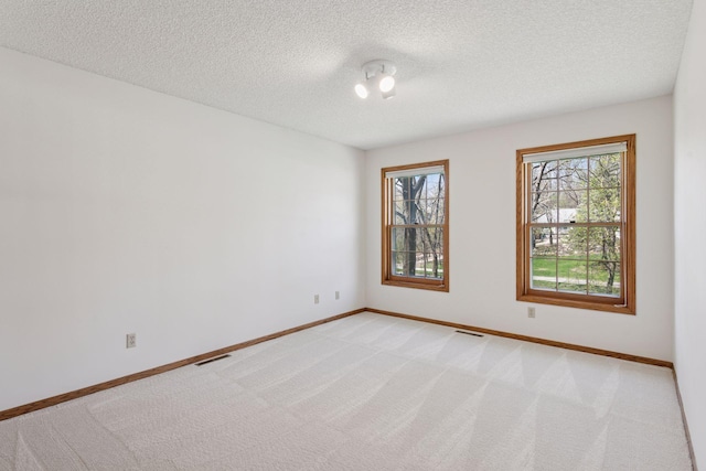 spare room featuring baseboards, light carpet, and visible vents