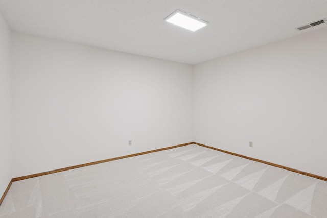 spare room with baseboards, visible vents, and light carpet