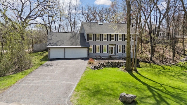 colonial inspired home with fence, a shingled roof, a garage, a front yard, and driveway