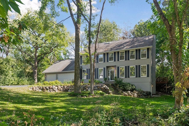 colonial house featuring a front lawn and a garage