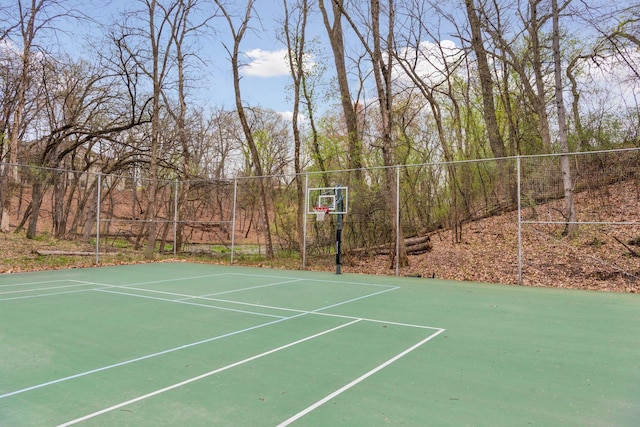 view of basketball court with fence and basketball hoop