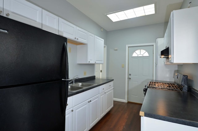 kitchen with white cabinetry, dark hardwood / wood-style floors, black fridge, and sink