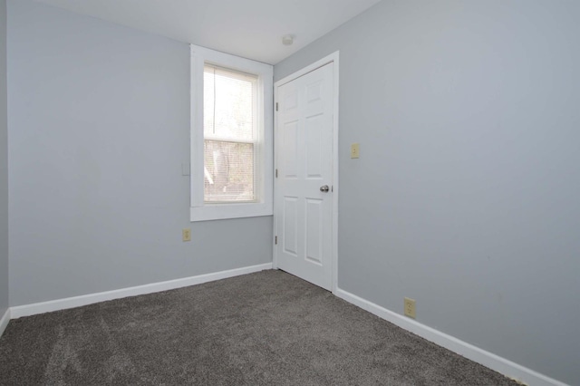 unfurnished room featuring dark colored carpet