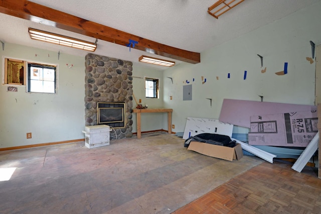 living room featuring a wealth of natural light, a textured ceiling, electric panel, and a stone fireplace