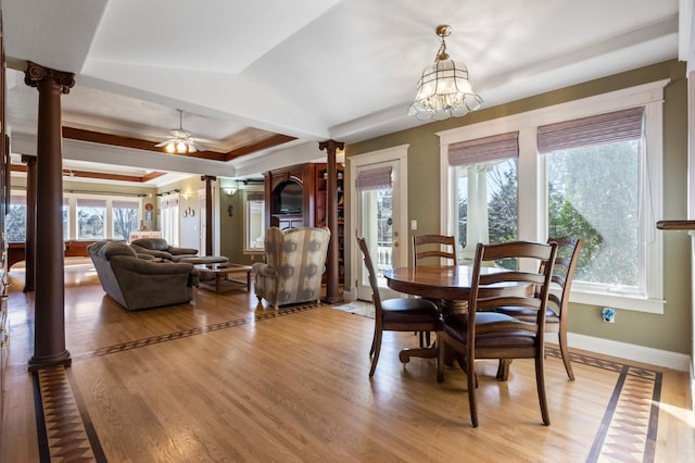 dining area with decorative columns, wood-type flooring, ceiling fan with notable chandelier, a raised ceiling, and ornamental molding