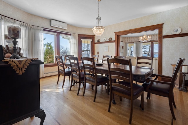 dining room featuring a healthy amount of sunlight, light hardwood / wood-style flooring, a wall mounted AC, and a notable chandelier