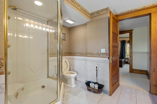 bathroom featuring tile floors, tile walls, enclosed tub / shower combo, toilet, and a textured ceiling