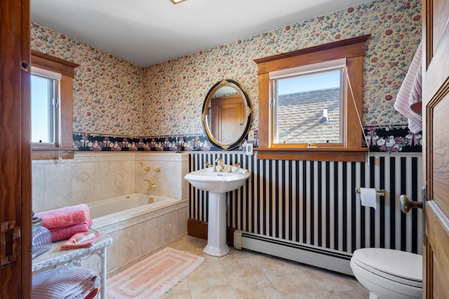 bathroom with a baseboard radiator, tile floors, toilet, and a relaxing tiled bath