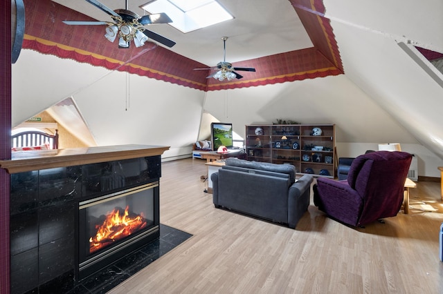 living room featuring a skylight, ceiling fan, hardwood / wood-style flooring, and a high end fireplace