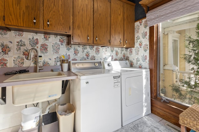 laundry area featuring light tile floors, washing machine and clothes dryer, cabinets, and sink