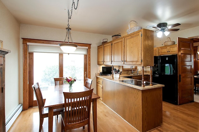 kitchen with black appliances, a baseboard radiator, kitchen peninsula, decorative light fixtures, and light hardwood / wood-style flooring