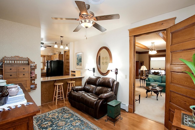 living room featuring light hardwood / wood-style flooring, a baseboard heating unit, and ceiling fan