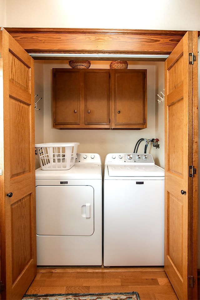 washroom with cabinets, washer and clothes dryer, and light wood-type flooring