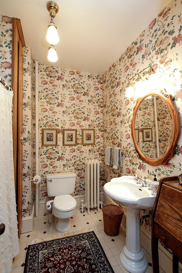 bathroom with toilet, radiator heating unit, and tile patterned flooring