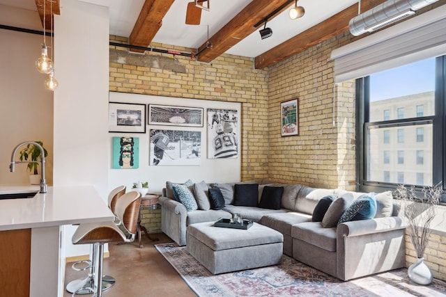 living room featuring concrete floors, brick wall, beamed ceiling, and sink