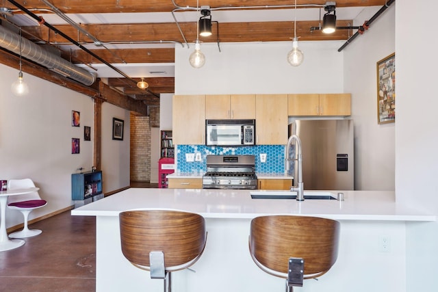 kitchen with tasteful backsplash, light brown cabinetry, stainless steel appliances, sink, and decorative light fixtures