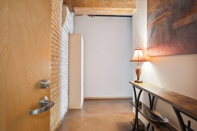 corridor featuring concrete floors and brick wall