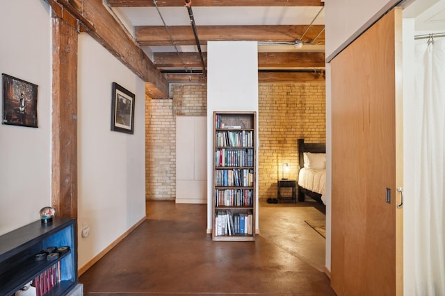 hall featuring beam ceiling and brick wall