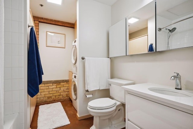 full bathroom featuring toilet, tiled shower / bath, vanity, and stacked washer and clothes dryer