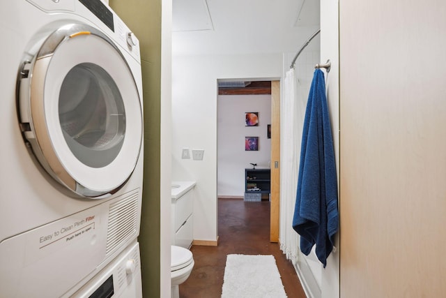 interior space featuring a shower with shower curtain, concrete flooring, toilet, vanity, and stacked washing maching and dryer