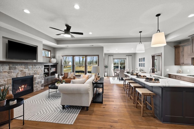 living room featuring ceiling fan, dark hardwood / wood-style flooring, a textured ceiling, a fireplace, and sink