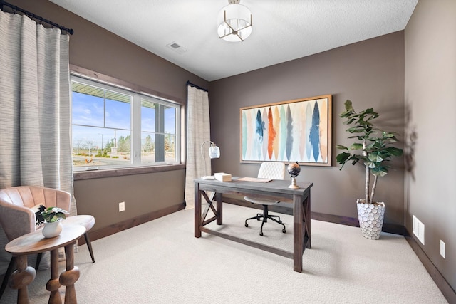 carpeted home office featuring a textured ceiling