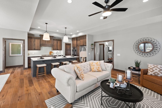 living room featuring ceiling fan, sink, and dark hardwood / wood-style floors