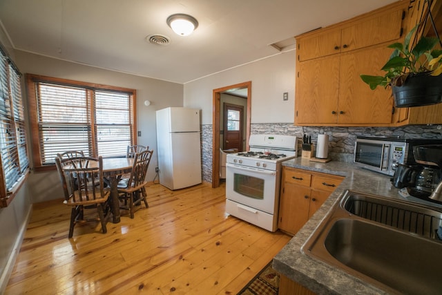 kitchen with light wood-type flooring, white appliances, tasteful backsplash, and a healthy amount of sunlight