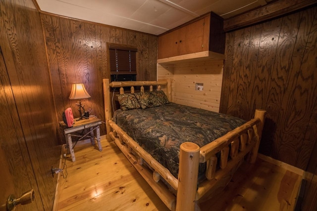 bedroom with wooden walls and light hardwood / wood-style floors