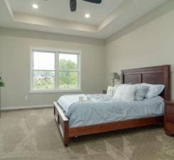 bedroom with ceiling fan and a tray ceiling