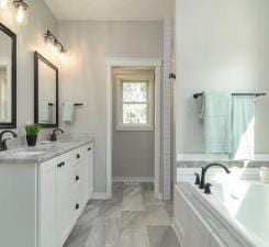 bathroom with tile flooring, a bath, and oversized vanity