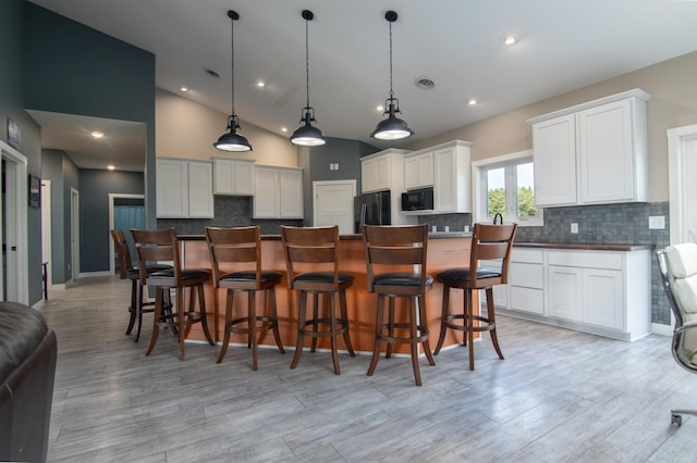 kitchen featuring black appliances, tasteful backsplash, white cabinetry, and a kitchen island