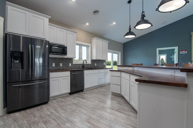 kitchen with tasteful backsplash, vaulted ceiling, pendant lighting, black appliances, and white cabinetry